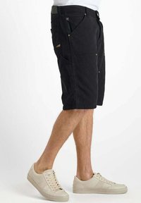 Zwarte cargoshorts met meerdere zakken, gemaakt van duurzaam materiaal. Kenmerken zijn een metalen rits, knoopsluiting en decoratieve stiksels.