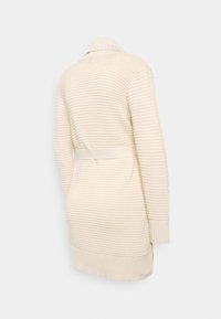 Béžový žebrovaný pletený kardigan s límcem, dlouhými rukávy, páskem v pase a rovný střihem, končící uprostřed stehen.