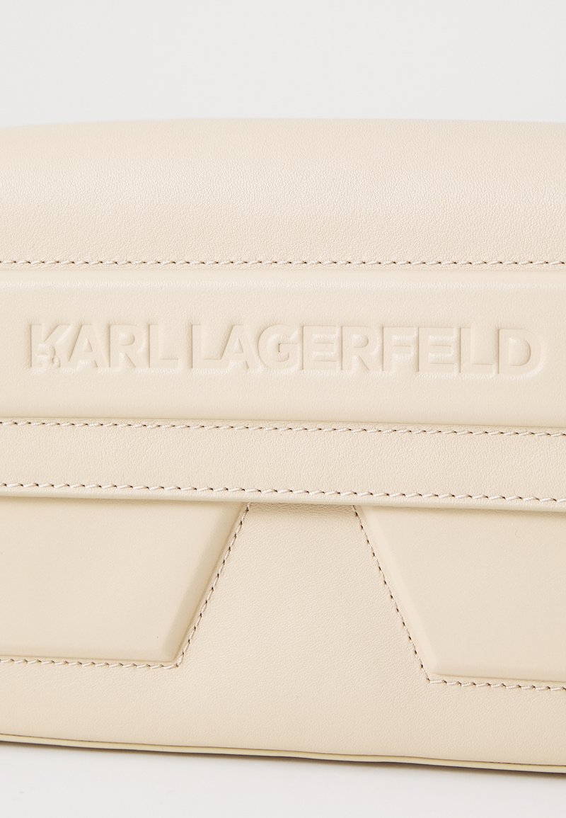 Beige Lederbeutel mit geprägt "KARL LAGERFELD" Logo, mit diagonalen Nähten und subtiler Textur, zeigt eine schlanke rechteckige Form.