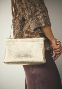 Goldene Metall-Clutch mit glattem, strukturiertem Finish. Verfügt über einen Kettenriemen und eine strukturierte rechteckige Form.