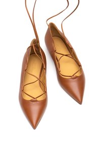 Ballerine in pelle marrone con punta affusolata e cinghie incrociate, dotate di una fodera interna beige. Texture liscia e design elegante per un look minimalista.
