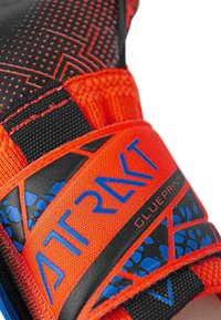 Orangene Sportschuh mit einem strukturierten schwarzen Riemen, blauen Akzenten und einer gemusterten Oberfläche. Verfügt über ein hervorgehobenes Logo und ein sicheres Verschlusssystem.