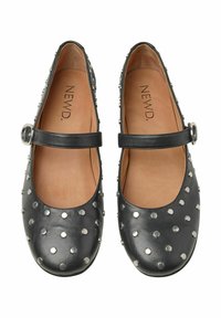 Svarta läderfinskor har en rund tå, dekorativa silvernitar och ett band med en metallspänne över fotryggen.