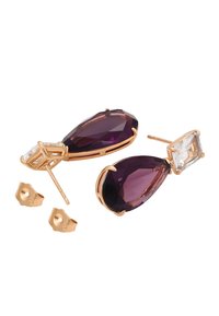 Zelta krāsas auskari ar lielu, facētotu purpura asaru formas akmeni un mazāku taisnstūra caurspīdīgu akmeni, kā arī iekļautu metāla sprādzi.