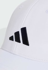 White cap made of smooth fabric, featuring black embroidered three-stripe logo on the front. Four ventilation eyelets visible.