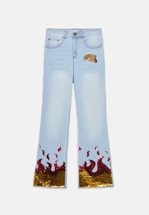 Lyseblå denim flare-jeans med flerfarget paljetterflamme-design i kanten og en lapp med grafikk på forsiden.