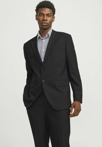 Schwarze Sakkojacke mit eingekerbtem Revers, zwei Knöpfen und Fronttasche. Über einem weißen Hemd mit navyblauen Streifen getragen, das einen klassischen Kragen aufweist.