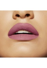 Rogue à lèvres mat dans une teinte mauve appliqué sur des lèvres pleines, mettant en évidence une texture lisse et des contours de lèvres définis sur un teint neutre.