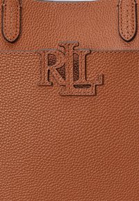 Ruda tekstūruota odinė rankinė su iškilniu "RL" logotipu priekyje, su dviem viršutiniais rankenomis nešti.