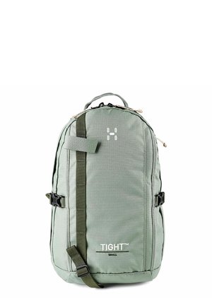 Compact groene rugzak met voorste band, zijgespen, bovenhandvat en witte "TIGHT Small" opdruk in het midden aan de voorkant.