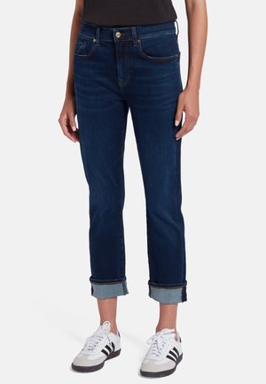 Jean bleu foncé avec une coupe droite, présentant des poignets roulés, une quincaillerie en bouton doré et un design classique à cinq poches. Texture en denim douce.
