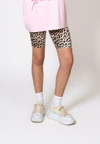 Animal print bike shorts with a beige and black leopard pattern, paired with a pink oversized t-shirt and white platform sneakers.