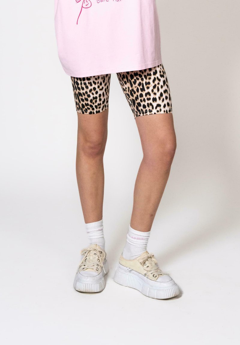 Animal print bike shorts with a beige and black leopard pattern, paired with a pink oversized t-shirt and white platform sneakers.