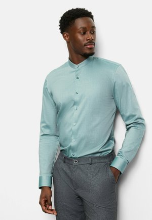 Light teal long-sleeve shirt with a mandarin collar, featuring a subtle texture and light blue buttons, paired with gray trousers.