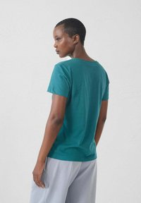 Teal katoenen t-shirt met een ronde hals en korte mouwen. De pasvorm is relaxed en de stof lijkt zacht met een gladde textuur.