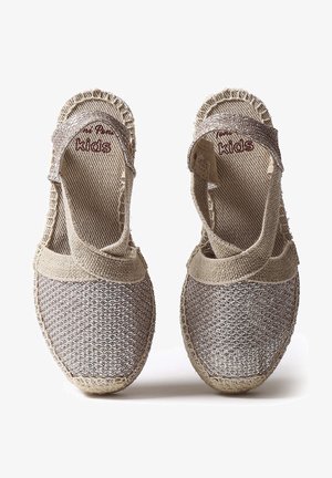 Zapatos de esparto en tono arena con parte superior tejido de color plateado, correas elásticas y suela de cuerda de yute. Diseño de talón abierto para mayor transpirabilidad y comodidad.