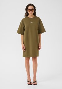 Olivově zelené oversized šaty z měkké bavlněné směsi s krátkými rukávy a kulatým výstřihem; na hrudi se nachází malé logo.