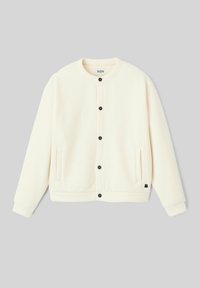 Veste couleur crème, texture côtelée, encolure ronde, fermeture à boutons avec boutons noirs, deux poches latérales et petit logo sur l'ourlet.