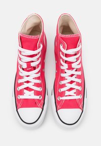 Sapatilhas altas em lona rosa brilhante com atacadores brancos, biqueiras em borracha e acabamentos pretos. Apresentam ilhós em metal e costura em contraste.