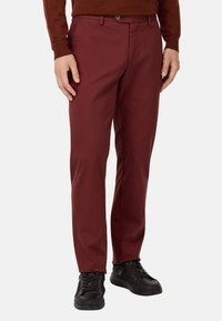 Bordo chinos ar taisnu piegriezumu, izgatavoti no viegla auduma. Iespējas: priekšējās kabatas, jostas cilpas un pogu aizdare. Valkāti ar melniem sporta apaviem.