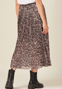 Gonna maxy plissettata con motivo leopardato, realizzata in materiale leggero e trasparente, con cintura elastica, abbinata a stivaletti neri..