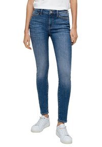 Jeans skinny in denim blu scuro, con vita alta, cinque tasche, leggera scoloritura e dettagli cuciti. Abbinati a sneakers bianche.