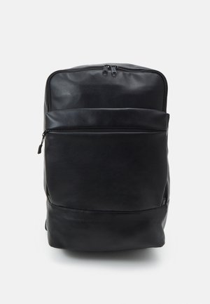 Schwarzer Lederrucksack mit zwei Reißverschlussfächern, einem großen Hauptfach und einer kleineren Fronttasche, vor einem schlichten hellen Hintergrund.