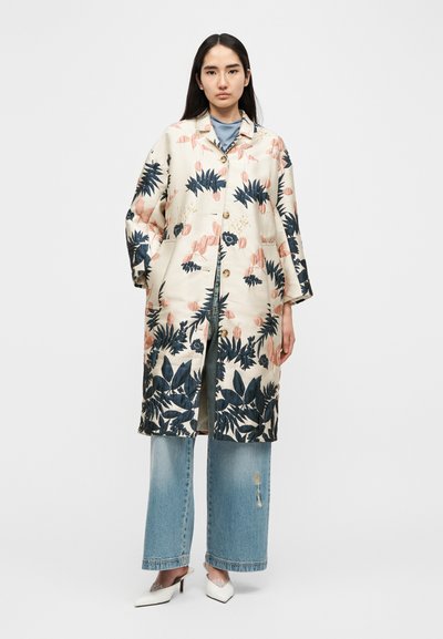 Manteau long à motif floral en crème avec des motifs bleus et roses, doté d'une fermeture boutonnée, de poches latérales et de manches à coupe décontractée.