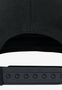 Interno di un cappellino da baseball nero con finitura in tessuto strutturato, caratterizzato da una visiera piatta e una cinghia regolabile con bottoni a pressione sul retro.