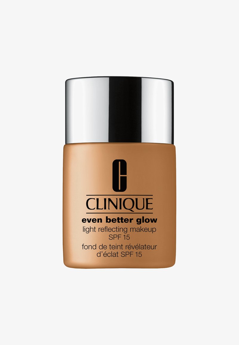 Clinique Even Better Glow foundation flaske; tan-farget plast med en blank sølvhette. Har merkevarelogo og produktdetaljer i svart tekst.