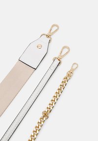 Drei Riemen: einer aus beigem Stoff mit goldfarbenen Beschlägen, einer aus weißem Leder mit schwarzem Rand und eine goldene Metallkette. Jeder hat Clips an den Enden.