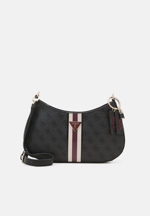 Schwarze Guess Schultertasche mit durchgehendem Logo-Muster, vertikalen weißen und burgunderfarbenen Streifen, goldfarbenen Beschlägen und zwei hängenden Markenanhängern.