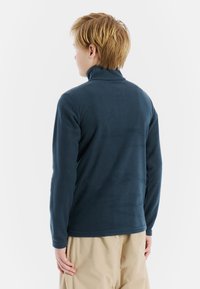 Pullover in pile blu scuro con colletto alto, maniche lunghe e texture morbida. Caratterizzato da un design semplice senza loghi o motivi visibili.