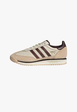 Beige suede and leather sneaker with dark brown stripes and accents. Rubber sole with a textured tread, vintage design, and logo details.