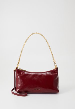Μπορντό δερμάτινη τσάντα χεριού με λεία υφή, χρυσή αλυσίδα και φερμουάρ κλεισίματος. Με ανάγλυφο λογότυπο στο μπροστινό μέρος. Συμπαγής σχεδίαση.