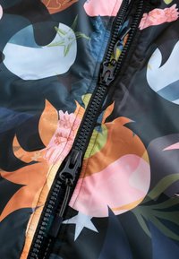 Mustast kangast riie erkroheliste, abstraktsete lillemustritega. Varustatud musta riistvaraga luku sulgemisega ja tekstuuri detailidega pinnal.