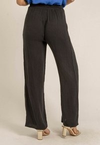 Pantalons noirs amples en tissu texturé avec une coupe large. Taille élastique et léger effet froissé sur l'ensemble.