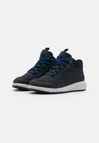 Tumedad sneakers mereel sinise kangas mustade detailidega. Omab tekstuuriga ülekatteid, siniseid paelu ja valget kummist välispinda. Ahnud, aga funktsionaalsed.