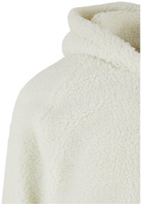 White, fluffy fleece hoodie with a high collar, featuring a soft texture and a slightly oversized fit.
