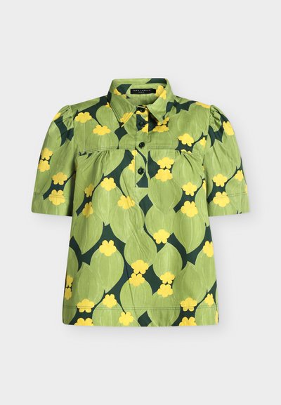 Blouse verte à manches courtes avec un col, des boutons noirs et un grand motif floral jaune et vert foncé.