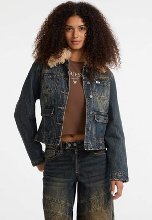 Denim jack met nep bontkraag, donkere wassing, cropped ontwerp, vier voorzakken en zilverkleurige knopen. Model draagt een bruine top en denim broek.