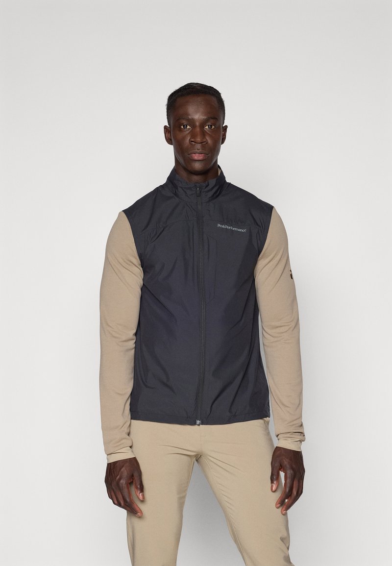 Sleeveless vest in dark gray, made of lightweight fabric. Features a high collar, front zipper, and logo on the chest. Smooth texture.