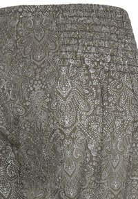 Tissu vert olive avec des motifs complexes de paisleys et de fleurs blancs en pointillés, doté de plis horizontaux près du bord supérieur.