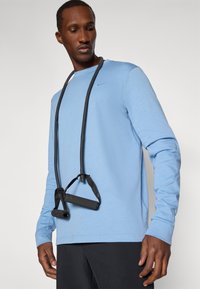 Šviesiai mėlyna ilgomis rankovėmis marškinėliai pagaminti iš minkštos medžiagos, su mažuoju logotipu ir juoda fitneso virve su rankena.