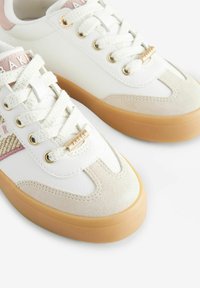 Sneakers bianchi con dettagli in camoscio e tessuto testurizzato. Presentano dettagli beige e rosa, occhielli dorati e una suola in gomma. Design con lacci e branding.