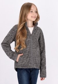 Giacca grigia con zip, dalla finitura testurizzata, colletto alto e tasche laterali, abbinata a jeans blu.
