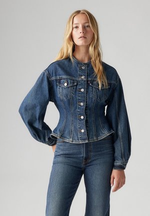 Džínová bunda s přiléhavým pasem, dlouhými balónovými rukávy, zapínáním na knoflíky a dvěma náprsními kapsami. Hluboká modrá barva s jemně vybledlými částmi.