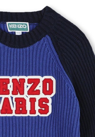 Pull en tricot avec un corps bleu à côtes et des manches marines, portant un grand logo blanc et rouge "KENZO PARIS" sur le devant.
