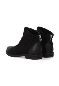 Para czarnych zamszowych botków za kostkę z panelami na obcasach ze skóry i srebrnymi zamkami błyskawicznymi z tyłu, prezentowana na białym tle.