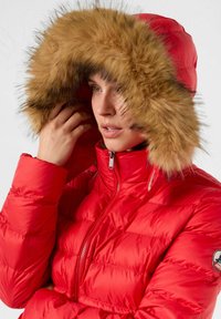 Giacca imbottita rossa con chiusura frontale a zip e collo alto, dotata di cappuccio con bordatura in pelliccia marrone. Tessuto trapuntato con finitura lucida.